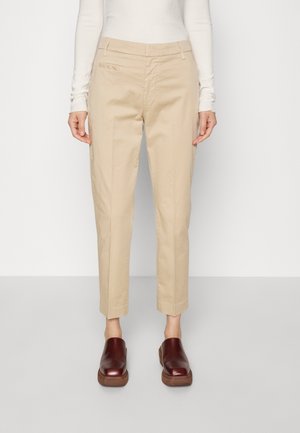Beige tapered chinos met een gladde katoentextuur, voorzien van zijzakken en een platte voorkant. Gecombineerd met bordeauxkleurige klompen.
