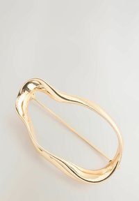 Guldtonet hårnål med et flydende, bølget design. Fremstillet af metal med en poleret overflade og en lige nål for sikker fastgørelse.