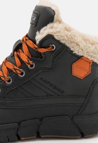 Bottine noire imperméable avec des lacets orange, doublure en fausse fourrure, semelle texturée et étiquette Geox. Ses caractéristiques comprennent un col rembourré et des coutures renforcées.