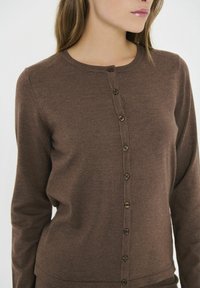 Brown button-up cardigan made of ribbed knit fabric. Features a round neckline, long sleeves, and six brown buttons down the front.