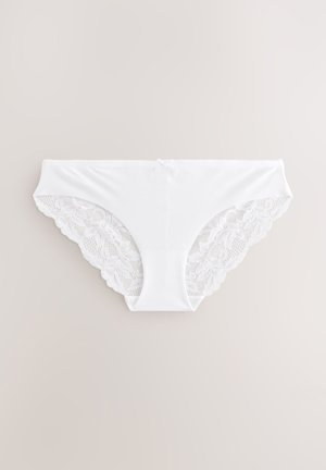 Fehér alsónadrág sima elülső résszel és bonyolult csipkerészlettel az oldalakon, hullámos szegéllyel és lágy anyagtextúrával.