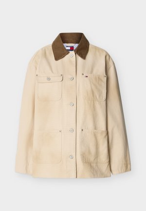 Μπεζ βαμβακερό μπουφάν με καφέ γιακά από κορντόρι, κουμπιά μπροστά και τέσσερις μπροστινές τσέπες, εκ των οποίων η μία έχει μικρό λογότυπο της μάρκας.