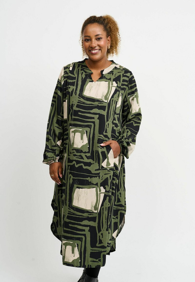 Rochie lungă, lejeră, de culoare neagră, cu modele geometrice verzi și bej. Prezintă un decolteu în V și buzunare, fiind realizată dintr-un material moale și având mâneci lungi.