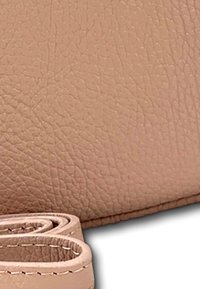 Portefeuille en cuir beige clair, avec une surface texturée, des bords arrondis et une sangle repliée avec des coutures décoratives.