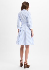 Blue and white striped dress with long sleeves, fitted waist, and flared skirt. Notable details include buttoned cuffs and a belt.