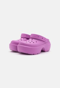 Zoccoli viola realizzati in materiale leggero. Presentano fori di ventilazione, una fascia posteriore e una suola testurizzata per una buona presa. Design a punta arrotondata.
