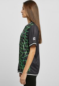 Sort trøje med grønt rutemønster, korte ærmer og hvide detaljer. Stoffet fremstår glat og let, designet til en afslappet pasform.