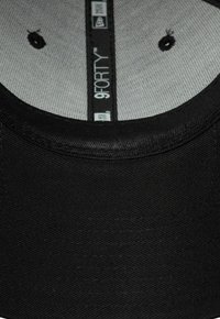Schwarze Kappe mit glatter Stofftextur, mit einer abgerundeten Krone und einem hellgrauen Innenfutter. Das Markenlabel ist im Inneren der Kappe sichtbar.