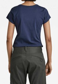 Granatowa bawełniana koszulka z okrągłym dekoltem i krótkimi rękawami, w połączeniu z ciemnozielonymi spodniami z tylnymi kieszeniami i naszywką.