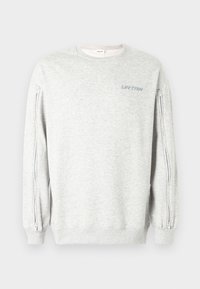 Ανοιχτό γκρι φούτερ με φερμουάρ στις πλευρικές ραφές, στρογγυλή λαιμόκοψη και μανσέτες με ρίγα. Φέρει το εκτύπωμα «UR TRN» σε ανοιχτό γαλάζιο χρώμα στο μπροστινό μέρος.