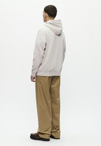 Light gray hoodie with a drawstring hood, paired with khaki wide-leg trousers. The outfit features simple design and soft textures.