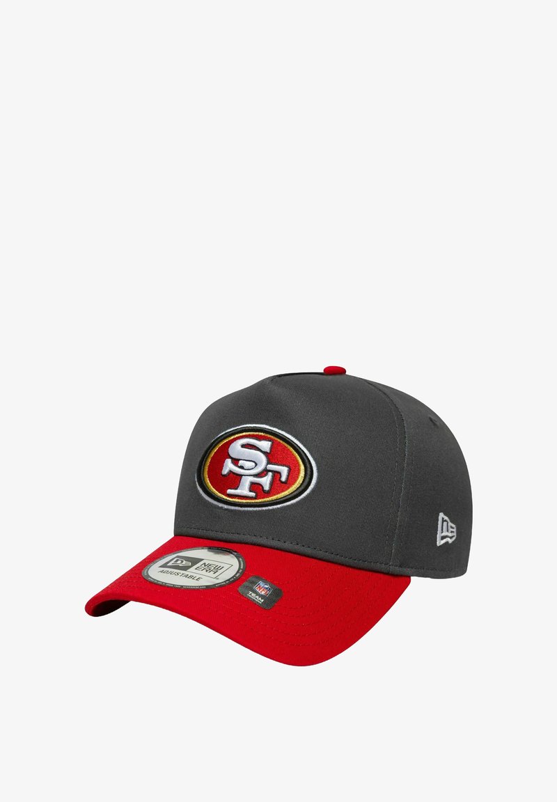 Gorra gris con visera roja. Presenta un logo circular bordado en rojo, dorado y blanco. Cinta ajustable en la parte trasera.