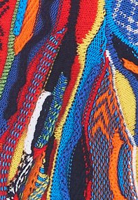Multifarvet strikket stof med bølgede mønstre i blå, rød, orange, grøn og gul. Den teksturerede overflade har forskellige strikketeknikker.