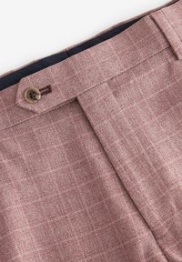 Helle rot karierte Stoffhose mit Knopfverschluss, ausgestattet mit einem marineblauen Innenfutter und glatter Textur. Sichtbare genähte Details entlang des Taillenbundes.