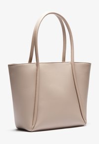 Beige läder tote-väska med mjuk textur, två långa handtag, rektangulär form och utan synlig hårdvara eller mönster.
