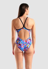 Costume da bagno intero multicolore con motivo floreale, design con schiena scoperta e spalline nere. Il materiale sembra liscio ed elastico.