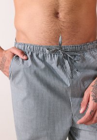 Shorts a righe grigie e bianche con vita elasticizzata, chiusura con cordoncino, tasche laterali e vestibilità rilassata.