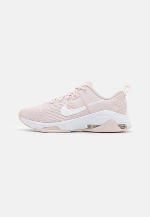 Scarpe sportive rosa chiaro con tomaia in rete, dettagli bianchi, suola imbottita e unità d'aria visibile nel tallone.