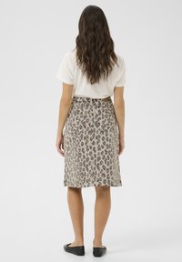 Léopardprint midi-rok in beige en bruintinten, met een rechte snit, achterzakken en een ceintuur in de taille, gecombineerd met zwarte flats.
