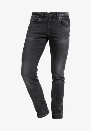 Jeans ajustados negros de denim, con cierre de cremallera, passadores para cinturón y un ligero desgastado. Incluye cinco bolsillos y detalles de costura mínimos.