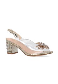 Gennemsigtig hæl-sandal lavet af transparent materiale, med et guldaccent og udsmykkede blomsterdetaljer på tæerne. Blokhæl med tekstureret overflade.