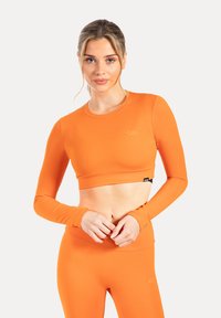 Langarm cropped top in helderrood, gemaakt van soepele stof. Beschikt over een ronde halslijn en een logo-detail op de linker borst.