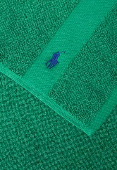 Πράσινη πετσέτα με υφή και μια πιο σκούρα πράσινη ρίγα που φέρει ένα μικρό κεντημένο μπλε λογότυπο παίκτη πόλο στο κέντρο.