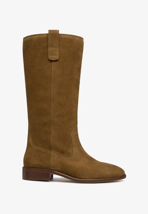 Botte en daim marron jusqu'au genou avec une silhouette droite, un talon plat et une sangle boucle en haut. Texture lisse et design à bout pointu.