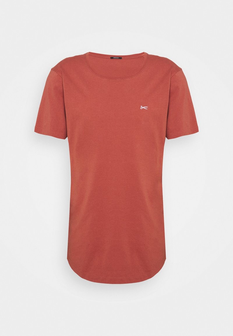 T-shirt à manches courtes couleur rouille avec encolure ronde et petite icône blanche de ciseaux sur la poitrine gauche.
