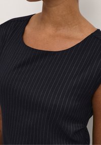 Haut sans manches marine avec un décolleté rond, présentant de fines rayures blanches et une texture de tissu lisse. Aucun motif ou accent supplémentaire.