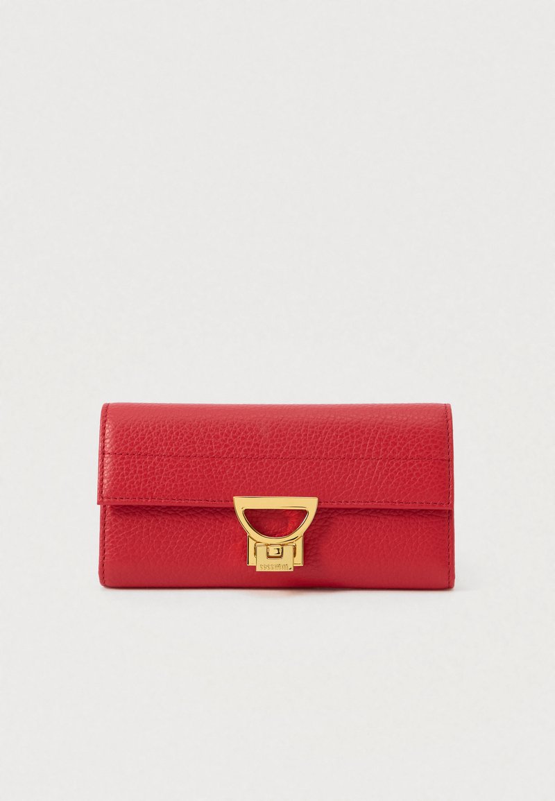 Raudonas tekstūruotas odinis piniginė su aukso tonų metaliniu užsegimu, stačiakampio formos ir su siuvinėtu ornamentu ant balto fono.
