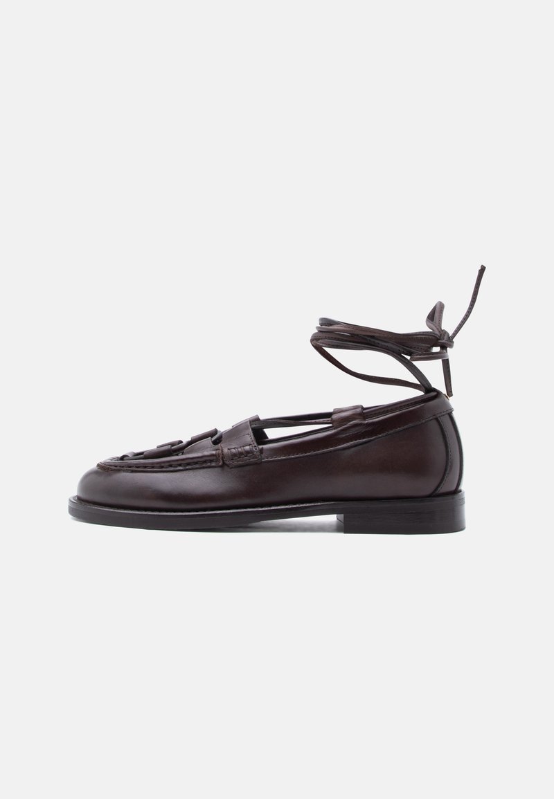 Καφέ σκούρα δερμάτινη μοκασίνι με κορδόνια που δένουν στον αστράγαλο, χαμηλό τακούνι και πλεκτή λεπτομέρεια στη λουρίδα πάνω από το άνω μέρος του ποδιού.