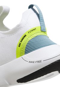 Talons de chaussures de running Nike blancs et bleu clair avec des accents vert néon, semelle texturée et textes "NIKE RUNNING FLYKNIT" et "NIKE FREE."