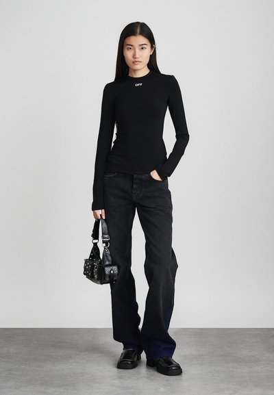 Bluza neagră cu mânecă lungă și logo alb, combinată cu o pereche de pantaloni din denim negri și o geantă mică din piele neagră cu ținte. Încălțăminte sunt ghete negre groase.