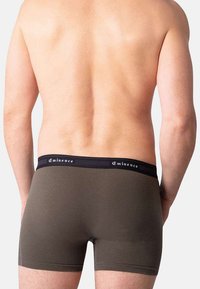 Boxers pour hommes en vert olive avec une texture lisse, avec une ceinture noire ornée du logo "Eminence". La vue arrière montre un design ajusté.