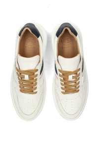 Witte leren sneakers met zwarte accenten, bruine veters, geperforeerde details en een gladde textuur. Crème kleurige binnenvoering zichtbaar.