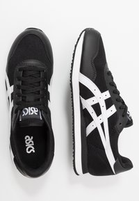 Black and white athletic sneakers with mesh and synthetic leather upper, featuring a lace-up design, white accents, and a textured sole.