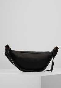 Sort stof skuldertaske med en buet form, justerbar rem, guldhardware-detaljer og glat tekstur. Minimalistisk design uden mønstre.