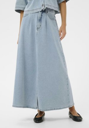 Light blue high-waisted denim maxi skirt with front slit, paired with black ballet flats and a cropped denim jacket.