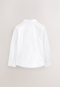 Chemise blanche à manches longues avec col et poignets boutonnés, présentant une texture lisse et un ourlet arrondi, affichée sur un fond neutre.