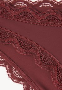 Bordeaux lingerie met kantafwerking, vervaardigd van een zachte stof, met bloemenkantaccenten langs de tailleband en decoratieve stikdetails.
