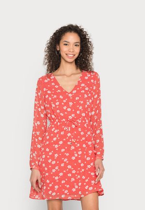 Vestido vermelho florido com mangas longas, decote em V e cintura ajustada. Apresenta pequenas flores brancas sobre um fundo texturizado.