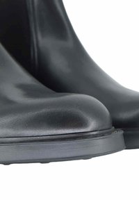 Czarne gumowe botki do kostki o gładkim wykończeniu, zaokrąglonym nosku i płaskiej podeszwie. Brak widocznych wzorów lub dodatkowych elementów ozdobnych.