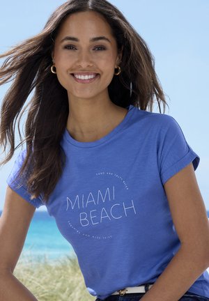 Blaues Baumwoll-T-Shirt mit einem kreisförmigen "Miami Beach"-Grafikdesign und Text. Das Design umfasst aufgerollte Ärmel und einen lässigen Schnitt.
