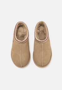 Bruine suède slippers met een zachte berenvoering, gestikte randen en een decoratieve rand rond de opening. Ontworpen voor comfort en warmte.
