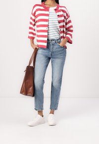 Cardigan a righe rosa e bianche, t-shirt a righe grigie e blu, jeans chiari a vita alta, sneakers bianche e borsa a tracolla marrone.