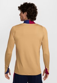 Pitkähihaista paitaa, kevyt kangas vaaleanbeige, jossa punaiset ja siniset yksityiskohdat kauluksessa ja hihoissa, sileä pintakuvio ja slim fit -muotoilu.