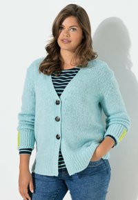 Světlomodrý pletený kardigan s výstřihem do V, se čtyřmi kulatými knoflíky a žebrovanými rukávy, doplněný proužkovaným topem pod ním.