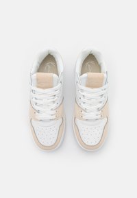 Hvite og beige sko med en glatt skinnfinish, perforert tåboks, snøring og teksturert stoffforing. Lettvektsdesign.
