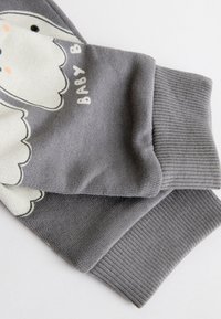 Hall hallipluus, millel on pehme valge elevandipilt. Värvilt veidi tumedamate hallide soonikkoes mansettidega. Pehme tekstuur ja lõdvestunud lõige.